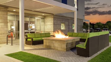 An outdoor seating area with a fire feature, a covered patio, and a view of the sky.