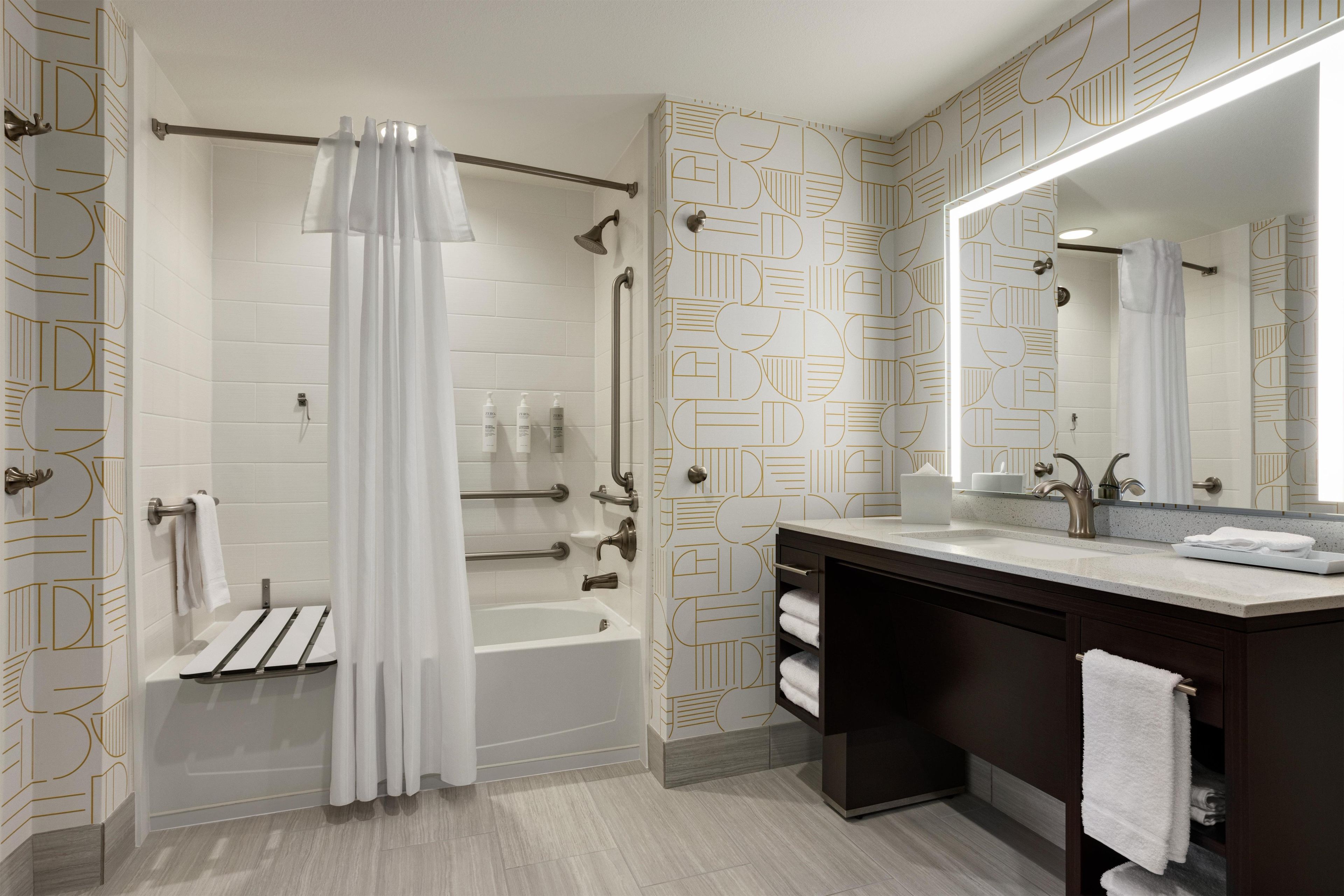 A modern bathroom with a walk-in shower, a vanity with a mirror, and a towel rack.