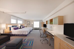 A hotel room with two beds, a desk, a TV, and a sofa.