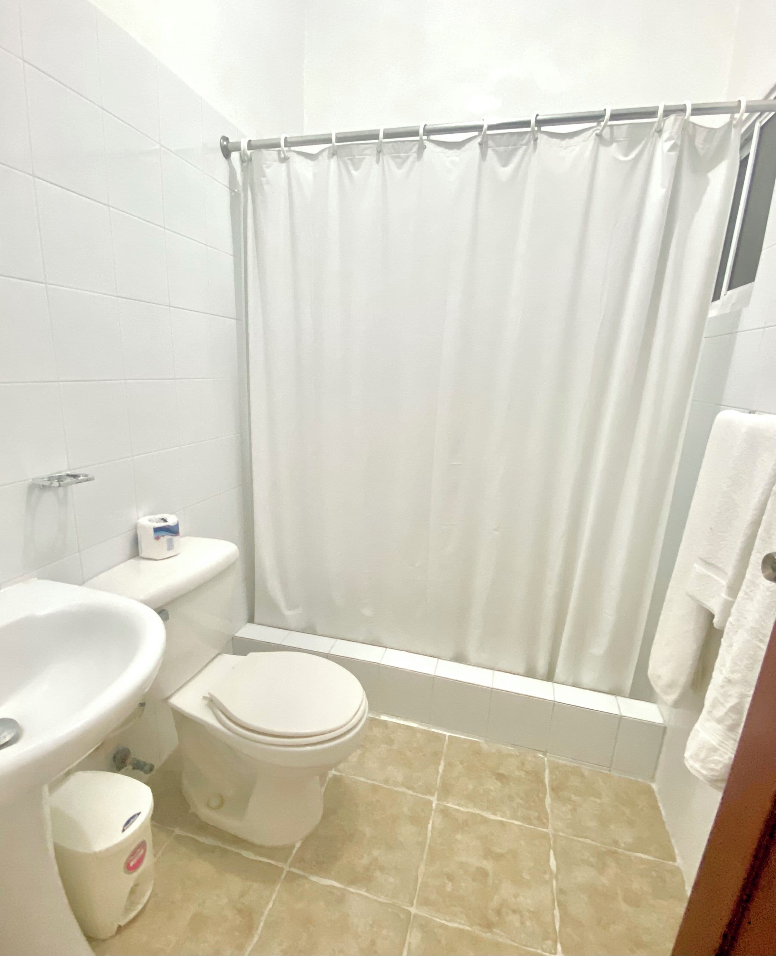 A small bathroom with a toilet, sink, and shower curtain.