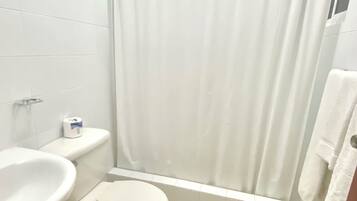 A small bathroom with a toilet, sink, and shower curtain.