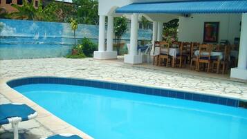Una piscina al aire libre, sillones reclinables de piscina