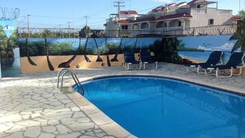 Una piscina al aire libre, sillones reclinables de piscina