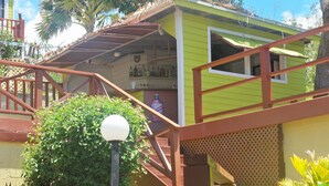 A small, brightly colored building with a staircase leading to a porch area. - The Ocean Inn (English Harbour)