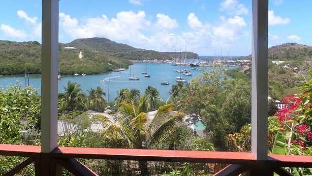 A view of a bay with boats, surrounded by greenery and hills. - The Ocean Inn (English Harbour)