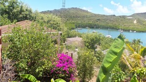 A coastal landscape with a clear view of a bay, boats, and lush greenery. - The Ocean Inn (English Harbour)
