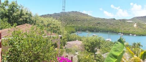 A coastal landscape with a clear view of a bay, boats, and lush greenery.