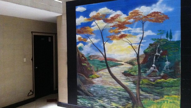 Un mural de un paisaje con árboles, un río y una cascada.