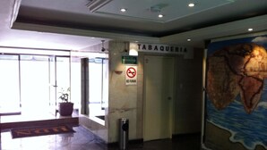 Un vestíbulo con un letrero que dice 'TABAQUERIA', un letrero de 'NO FUMAR' y un gran mural de un globo terráqueo.