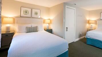 A hotel room with a large bed, two bedside tables, a door, and two wall-mounted lamps.
