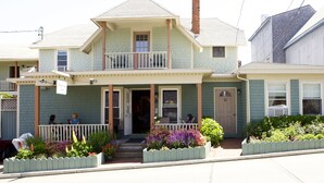 A two-story house with a balcony, a front porch, and a small garden. - Madison Inn (Oak Bluffs)