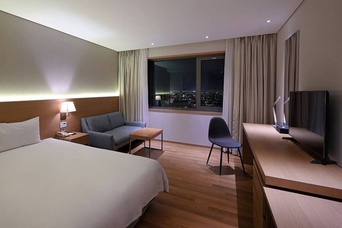 Una habitación de hotel con una cama grande, un escritorio con una silla, un sofá y un televisor.