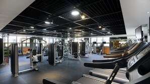 Un gimnasio con cintas de correr, máquinas de pesas y un espejo grande.