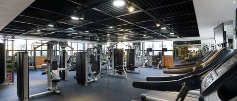 A gym with treadmills, weight machines, and a mirrored wall.