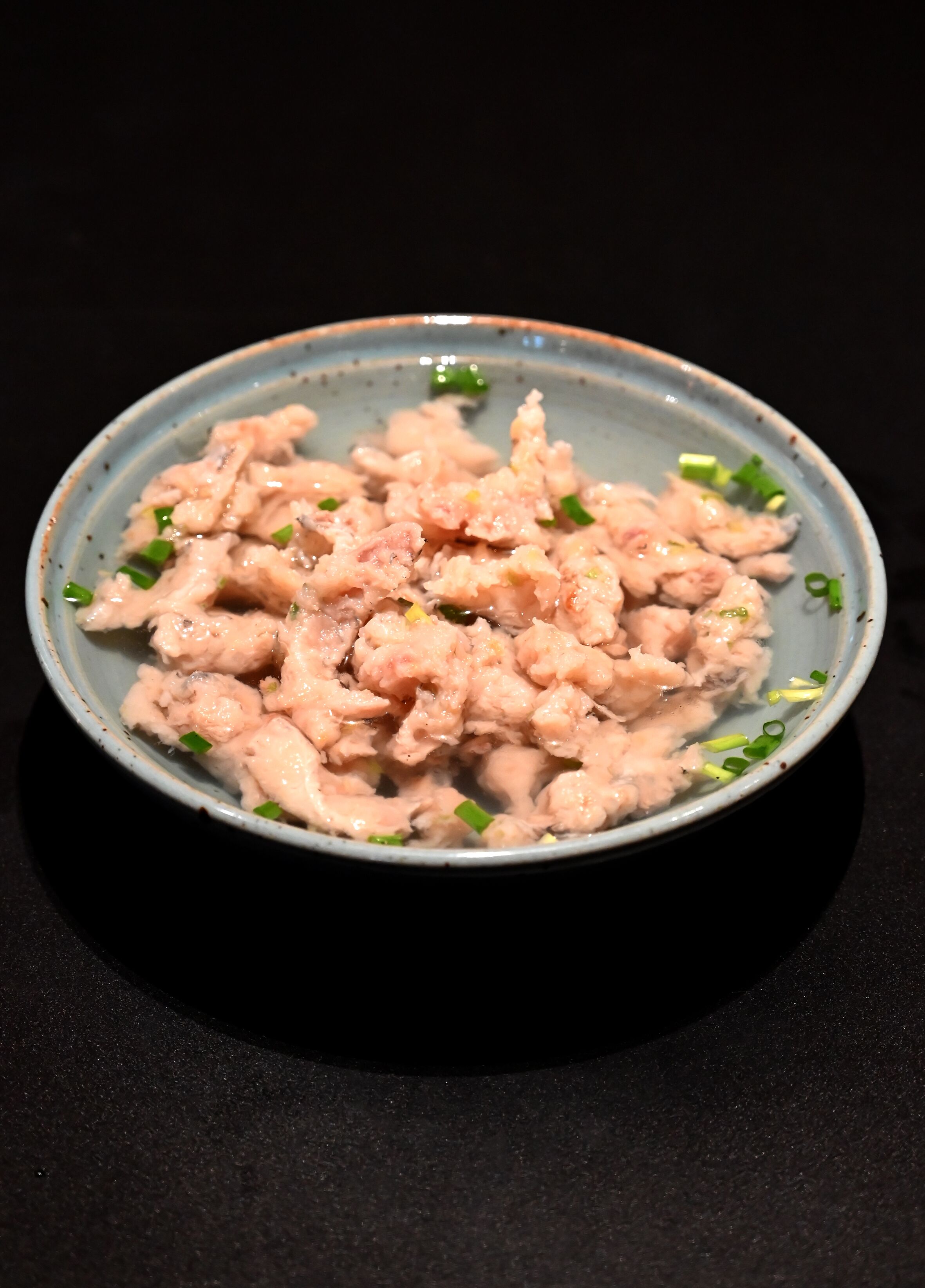 A bowl of food with green garnishes.