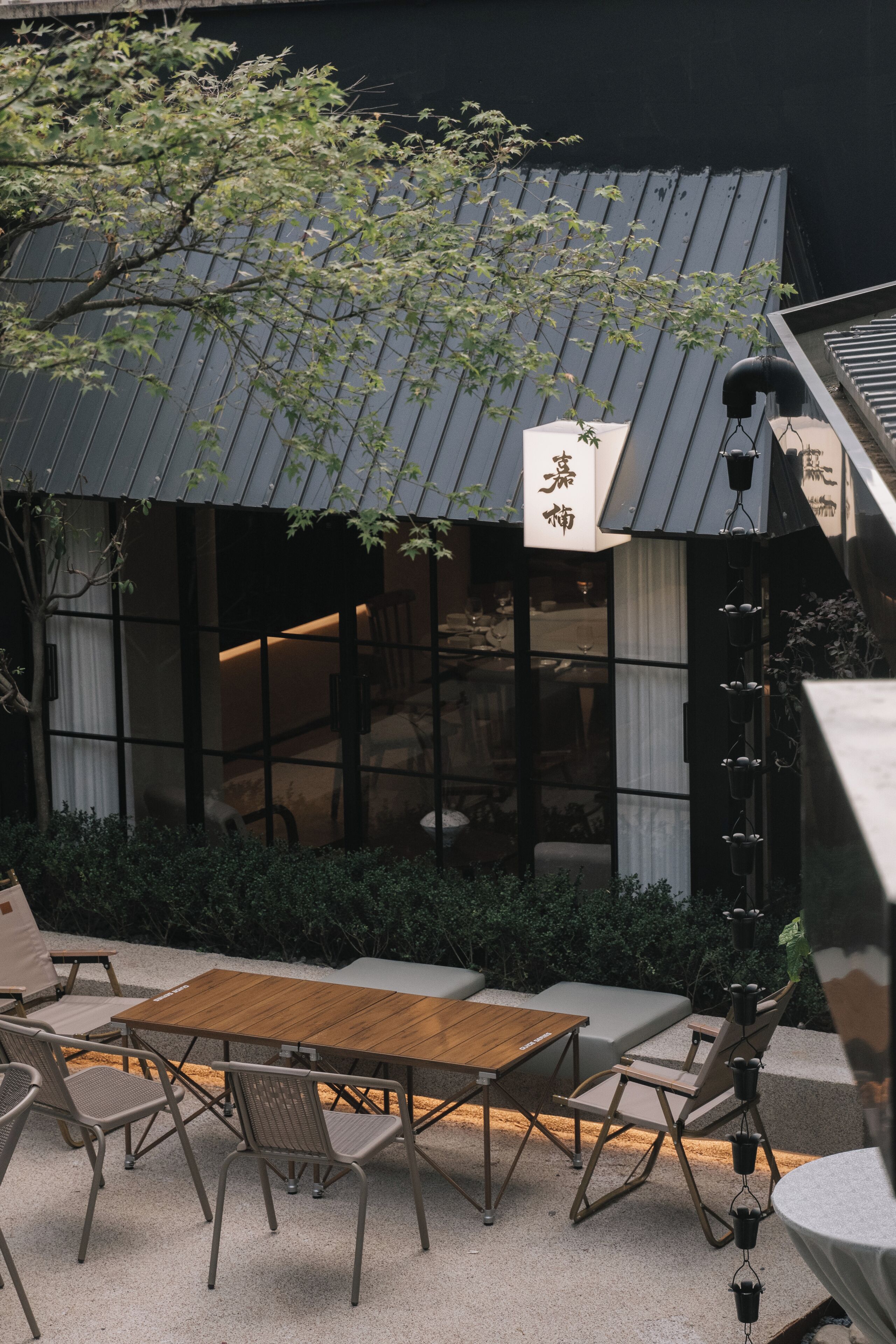 A restaurant with a wooden table and chairs, a black awning, and a sign with Japanese characters.