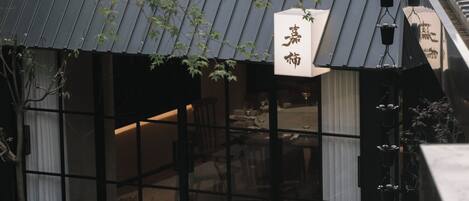 A restaurant with a wooden table and chairs, a black awning, and a sign with Japanese characters.