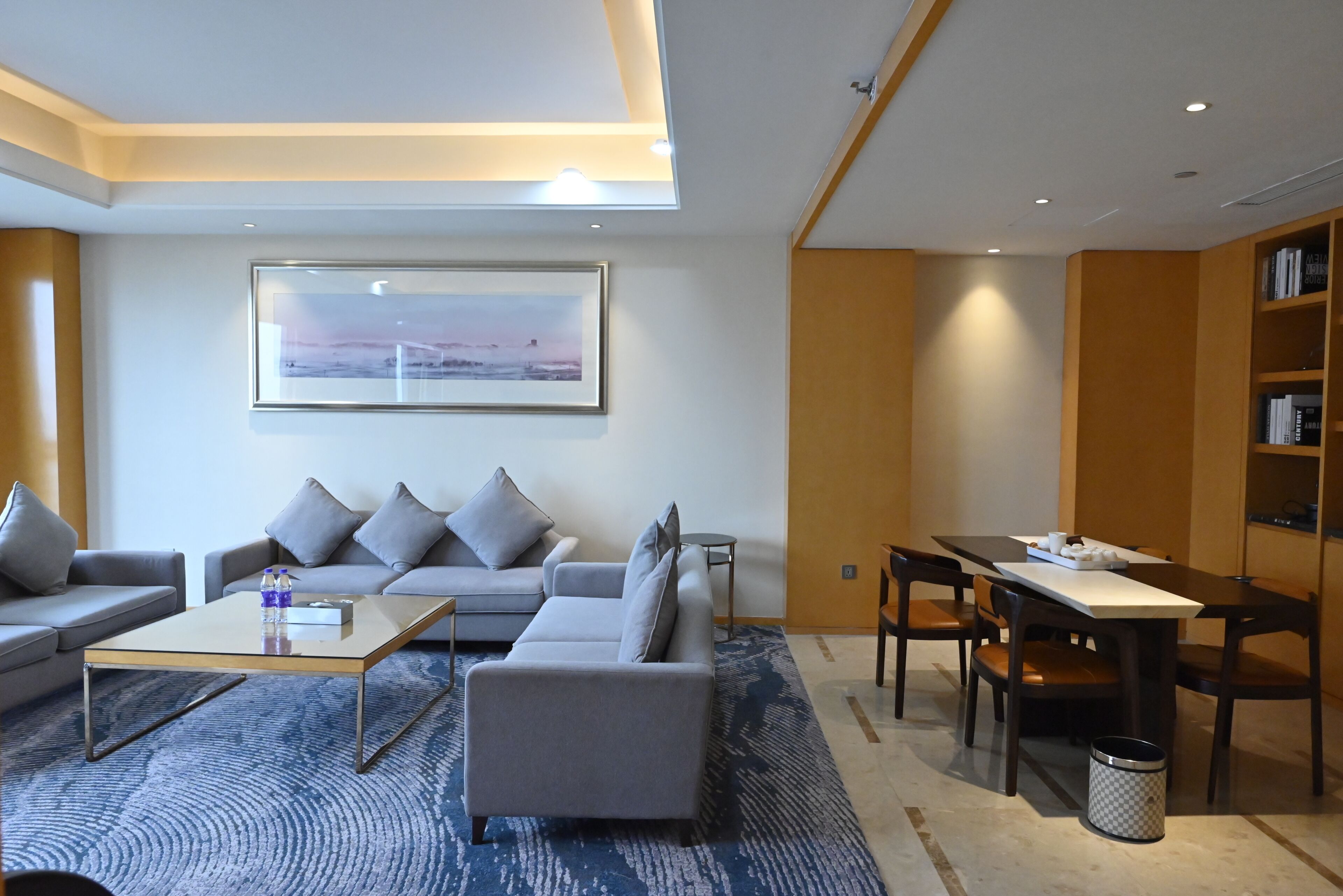 A modern living room with a sofa, coffee table, and a dining area with chairs and a table.