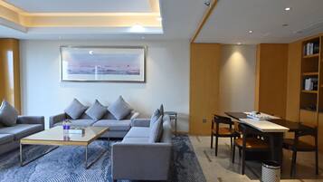 A modern living room with a sofa, coffee table, and a dining area with chairs and a table.