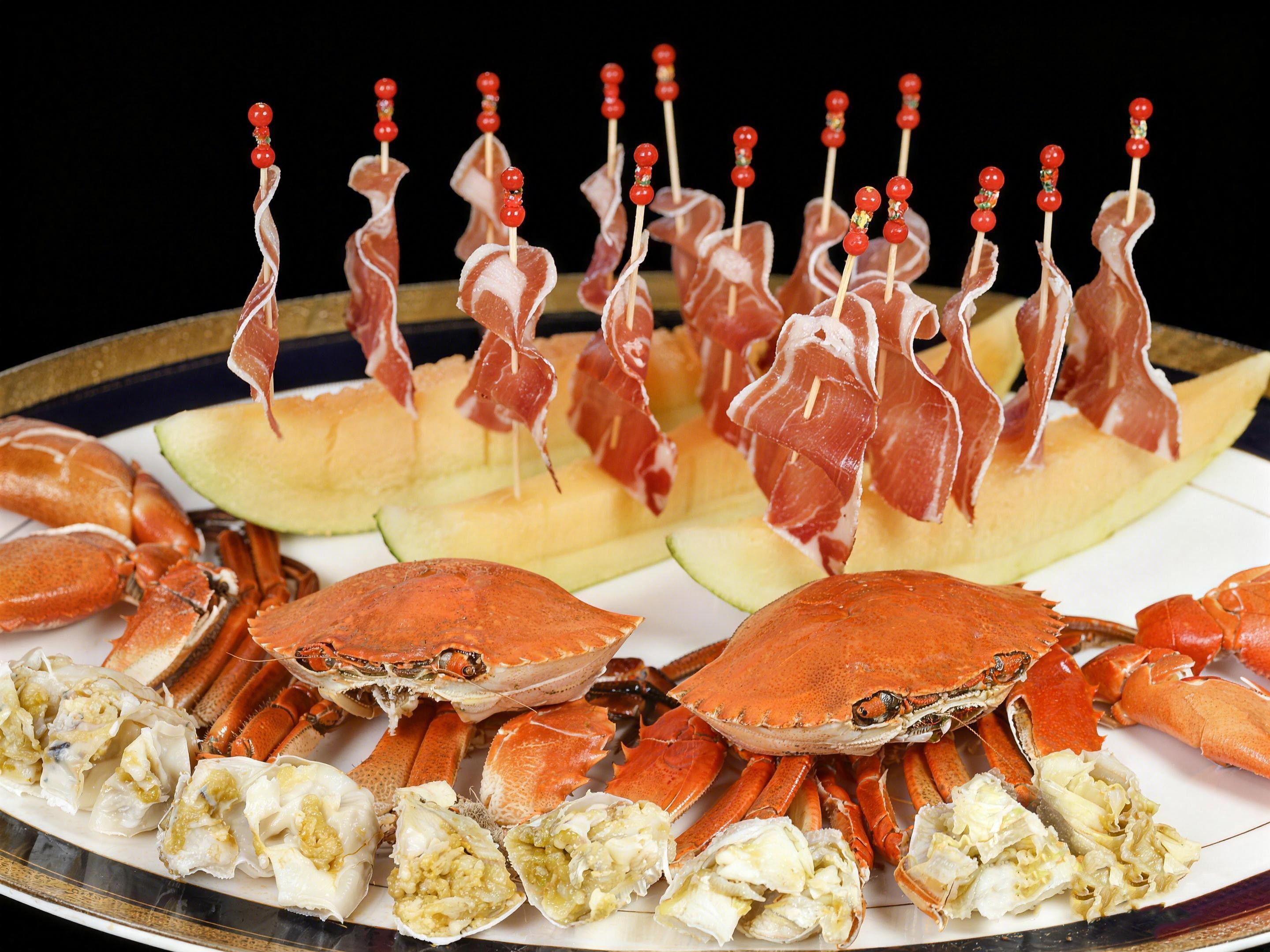 Un plateau de fruits de mer comprenant des pinces de crabe, des brochettes de viande et des tranches de melon.