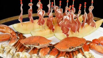 Un plateau de fruits de mer comprenant des pinces de crabe, des brochettes de viande et des tranches de melon.