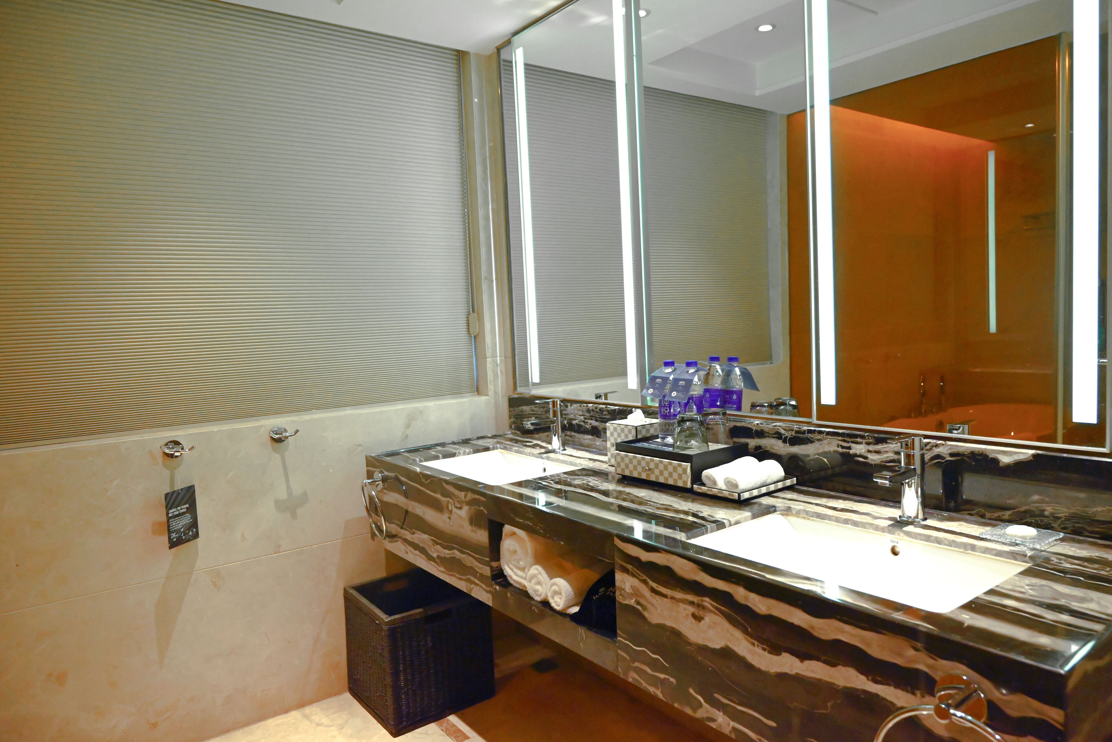 A modern bathroom with two sinks, a large mirror, and a towel rack.