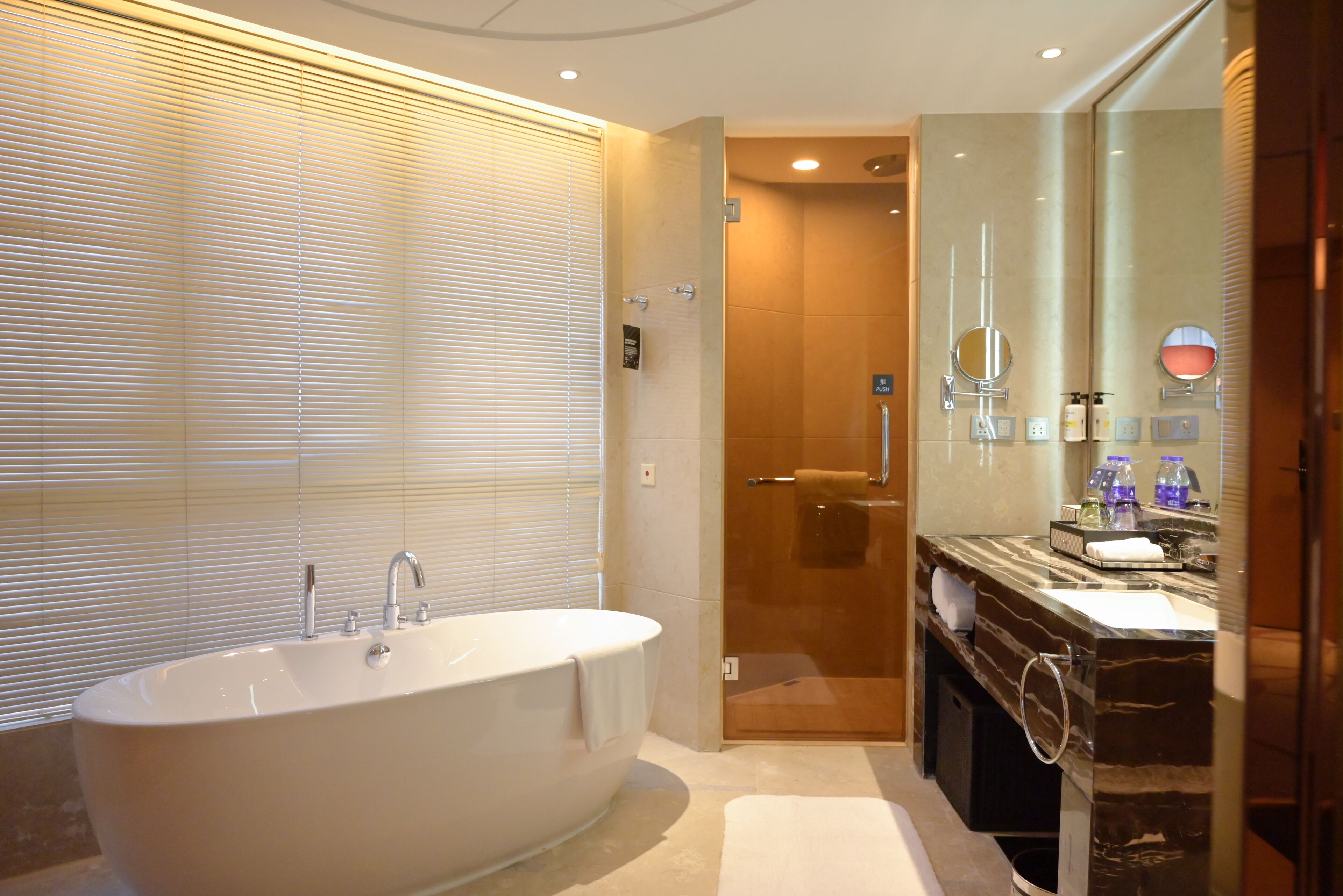 A modern bathroom with a freestanding bathtub, a glass-enclosed shower, and a marble vanity with a mirror.