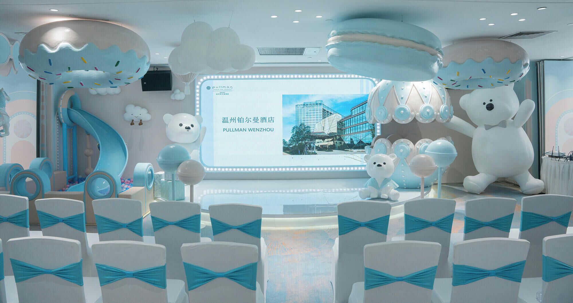 Un espace de jeux pour enfants avec des toboggans, une grande statue d’ours et une enseigne d’hôtel Pullman Wenzhou.