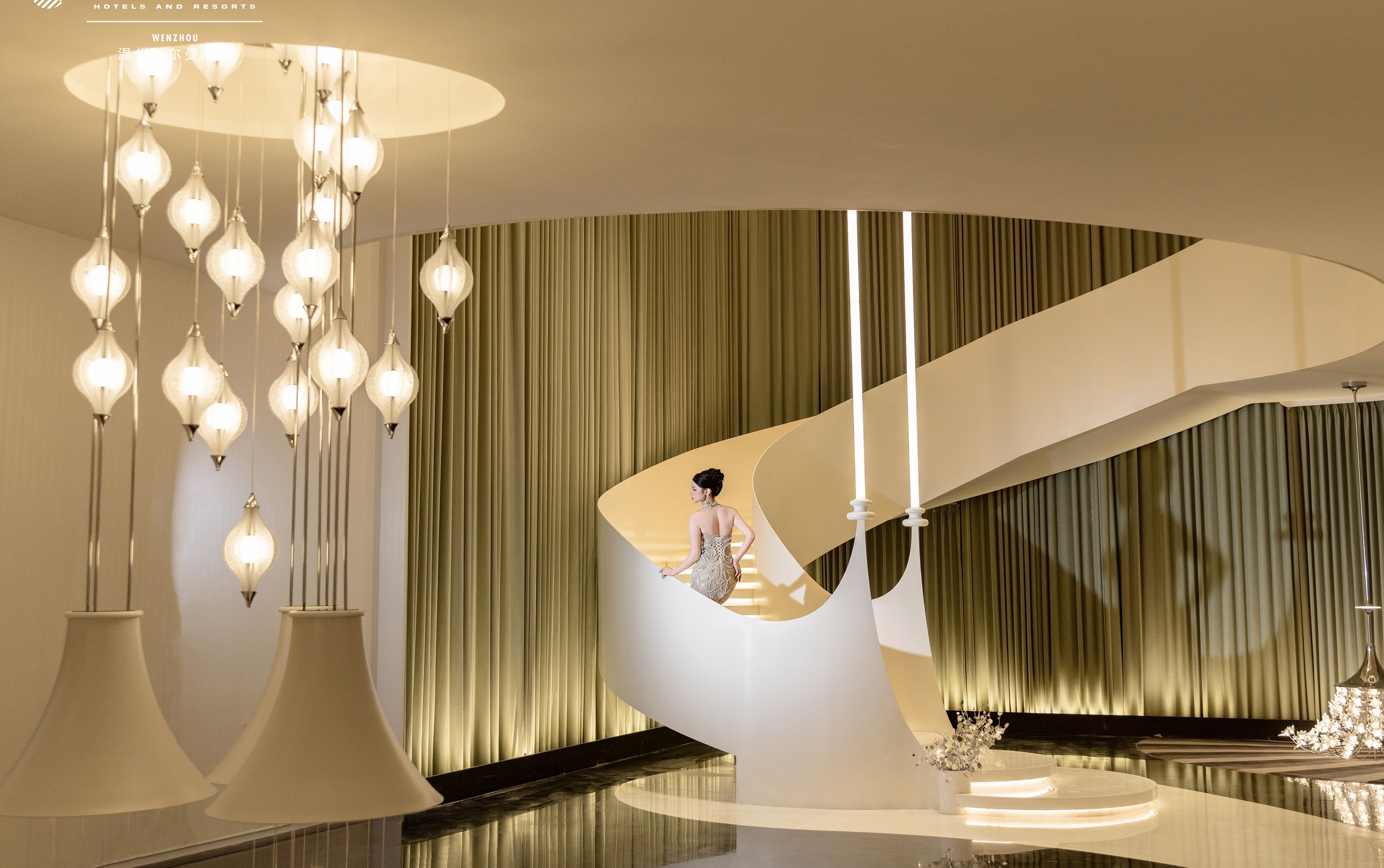A modern hotel interior with a unique spiral staircase, elegant lighting fixtures, and a minimalist design.