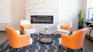 A modern lounge area with two white armchairs, a round coffee table, and a stone fireplace. - Dormir (Windham)