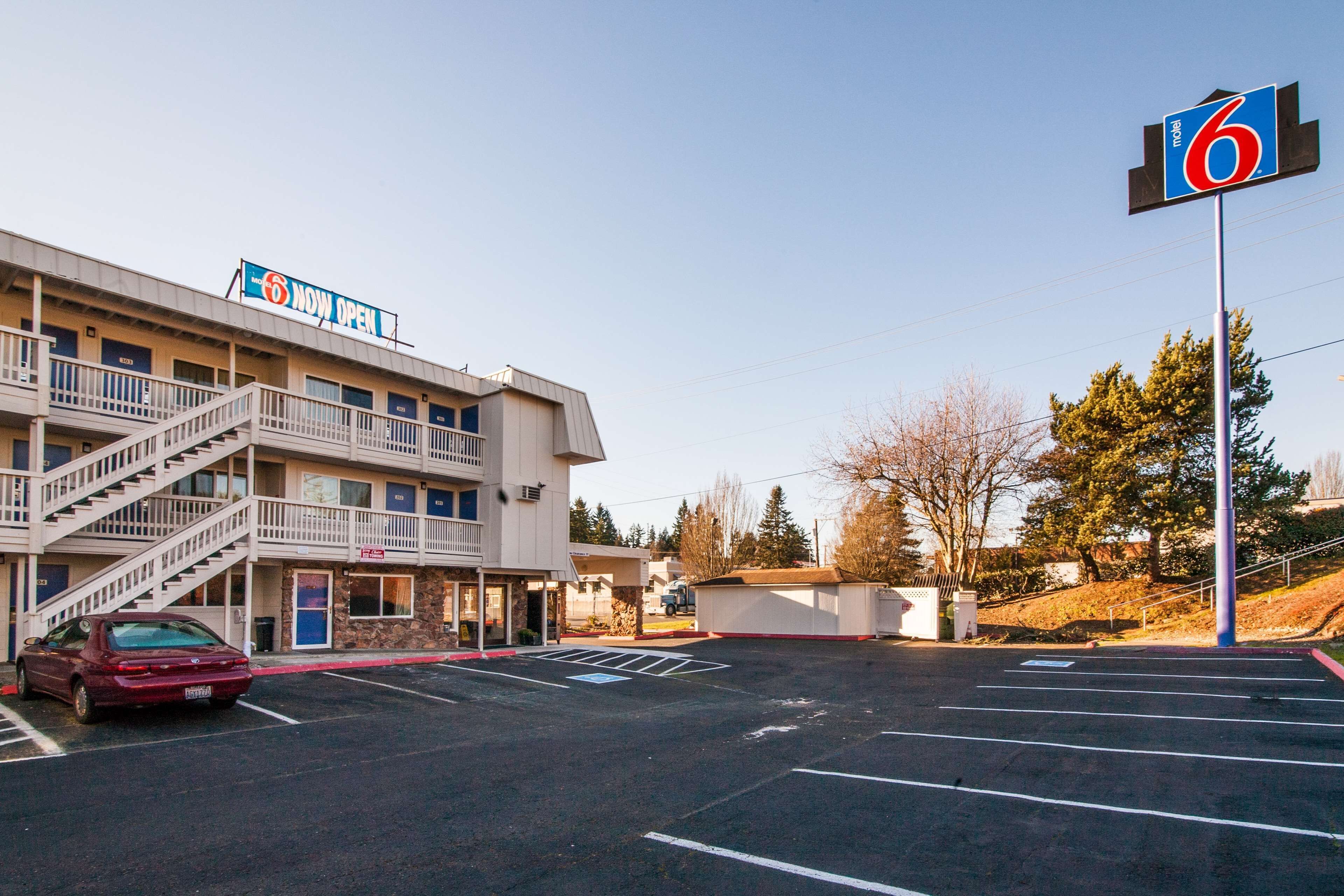 A motel with a 'Now Open' sign, a parking lot, and a '6' sign.
