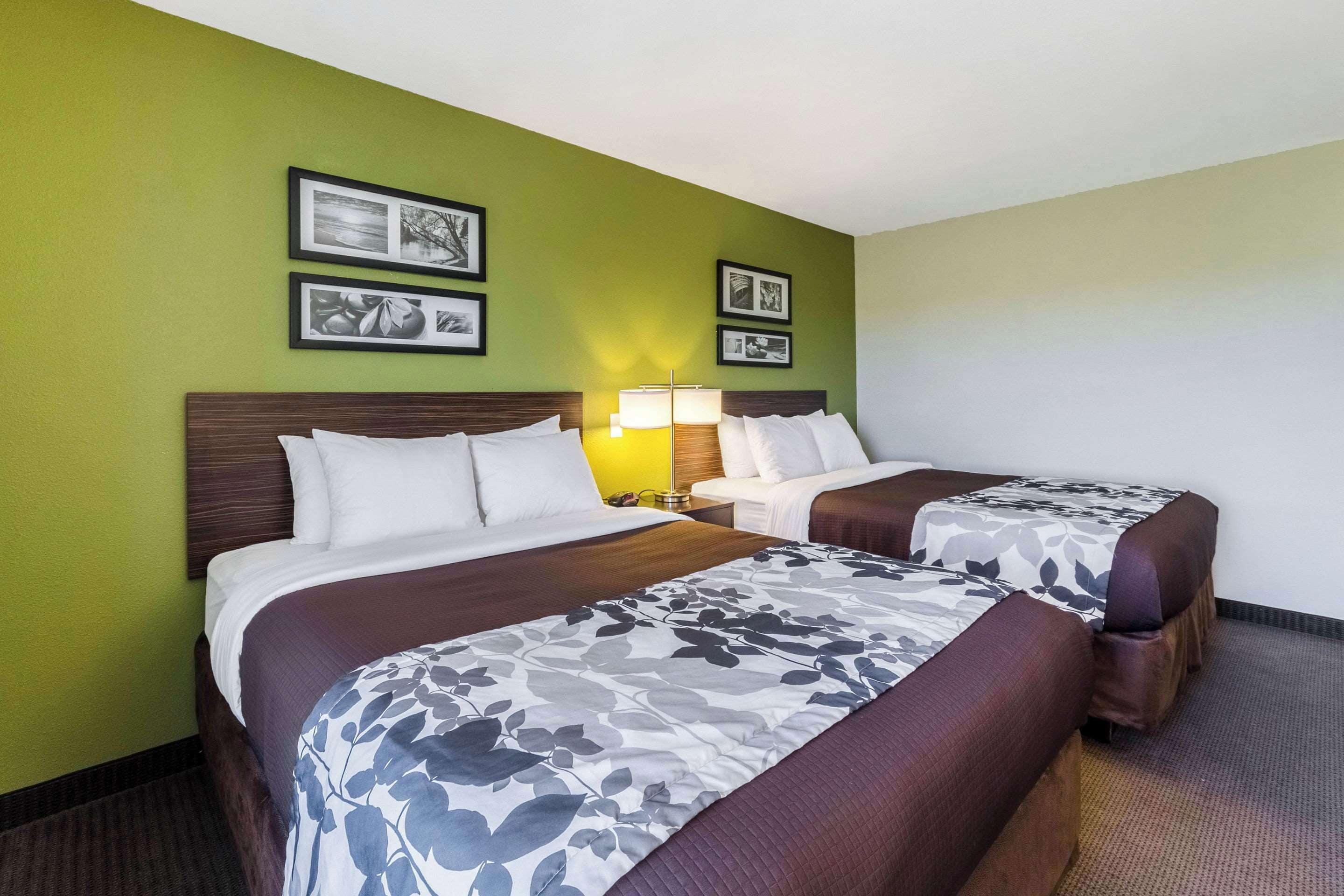 A hotel room with two beds, green walls, and framed pictures on the wall.
