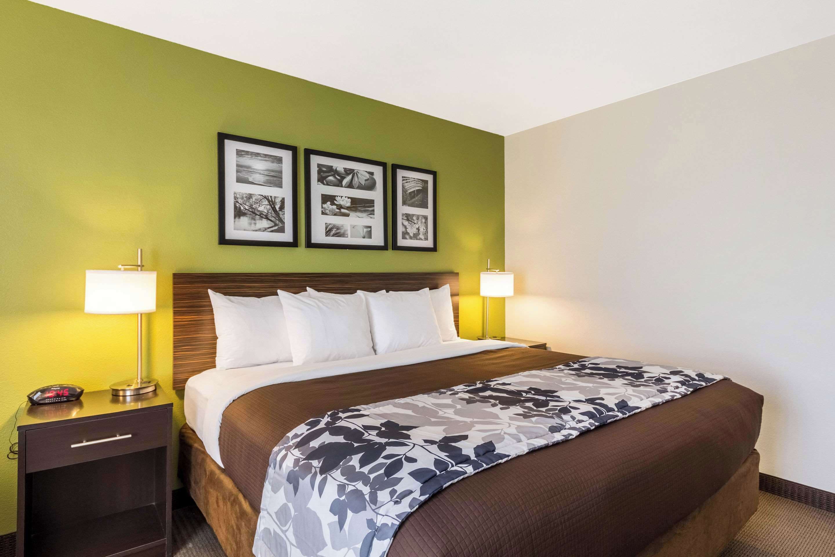 A hotel room with a bed, two bedside lamps, a nightstand, and three framed pictures on the wall.