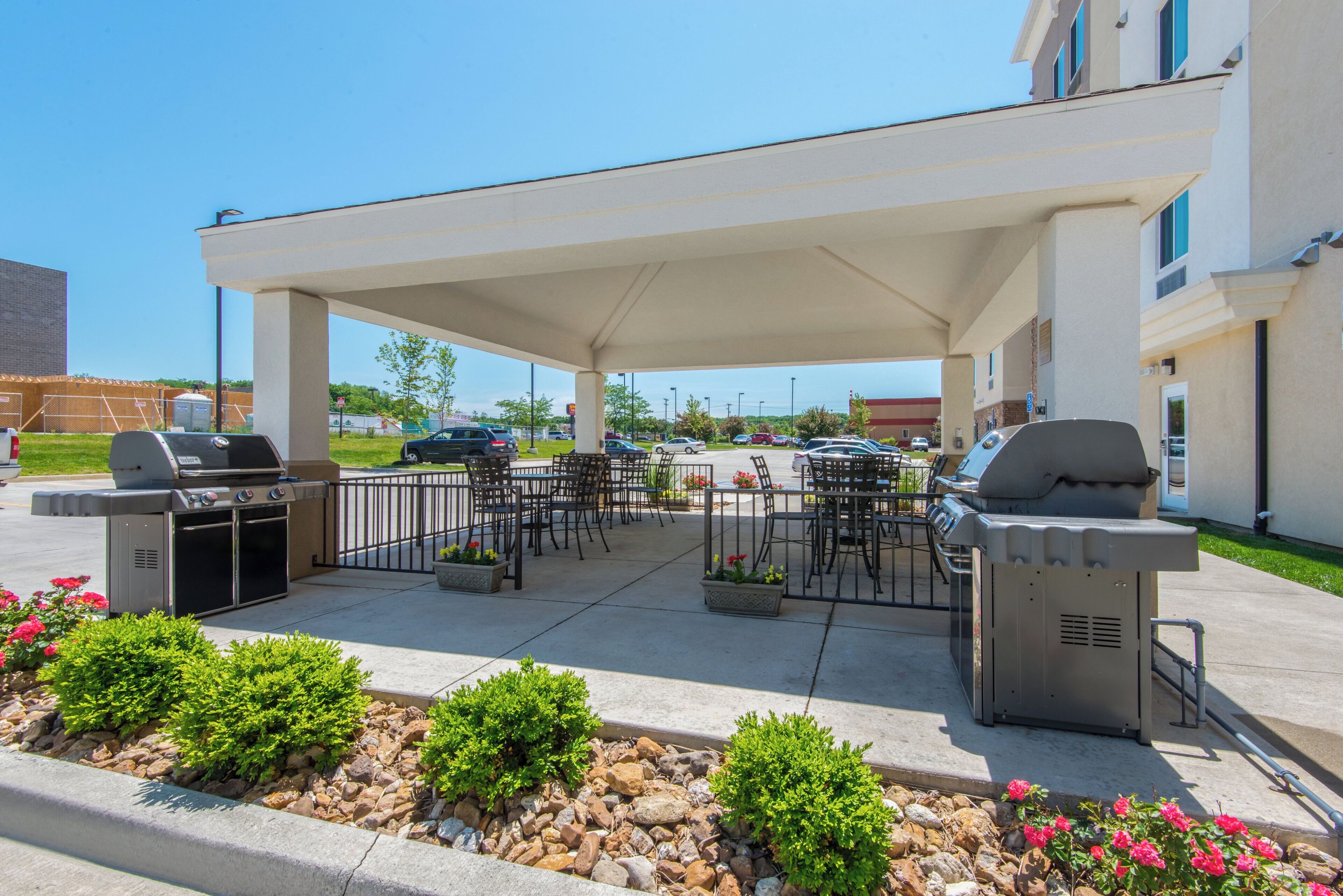 An outdoor patio area with barbecue grills, seating, and a covered walkway.