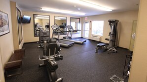 Une salle de sport équipée de tapis de course, d’appareils de musculation et d’un mur recouvert de miroirs.