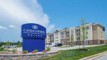 Un letrero de hotel con 'CANDLEWOOD SUITES' y un edificio de varios pisos con fachada de piedra.