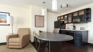 Habitación de hotel moderna con comedor, sofá, televisión de pantalla plana, microondas y cafetera.