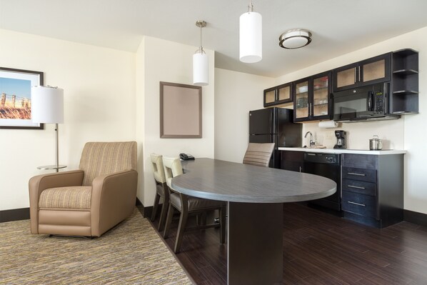 Habitación de hotel moderna con comedor, sofá, televisión de pantalla plana, microondas y cafetera.