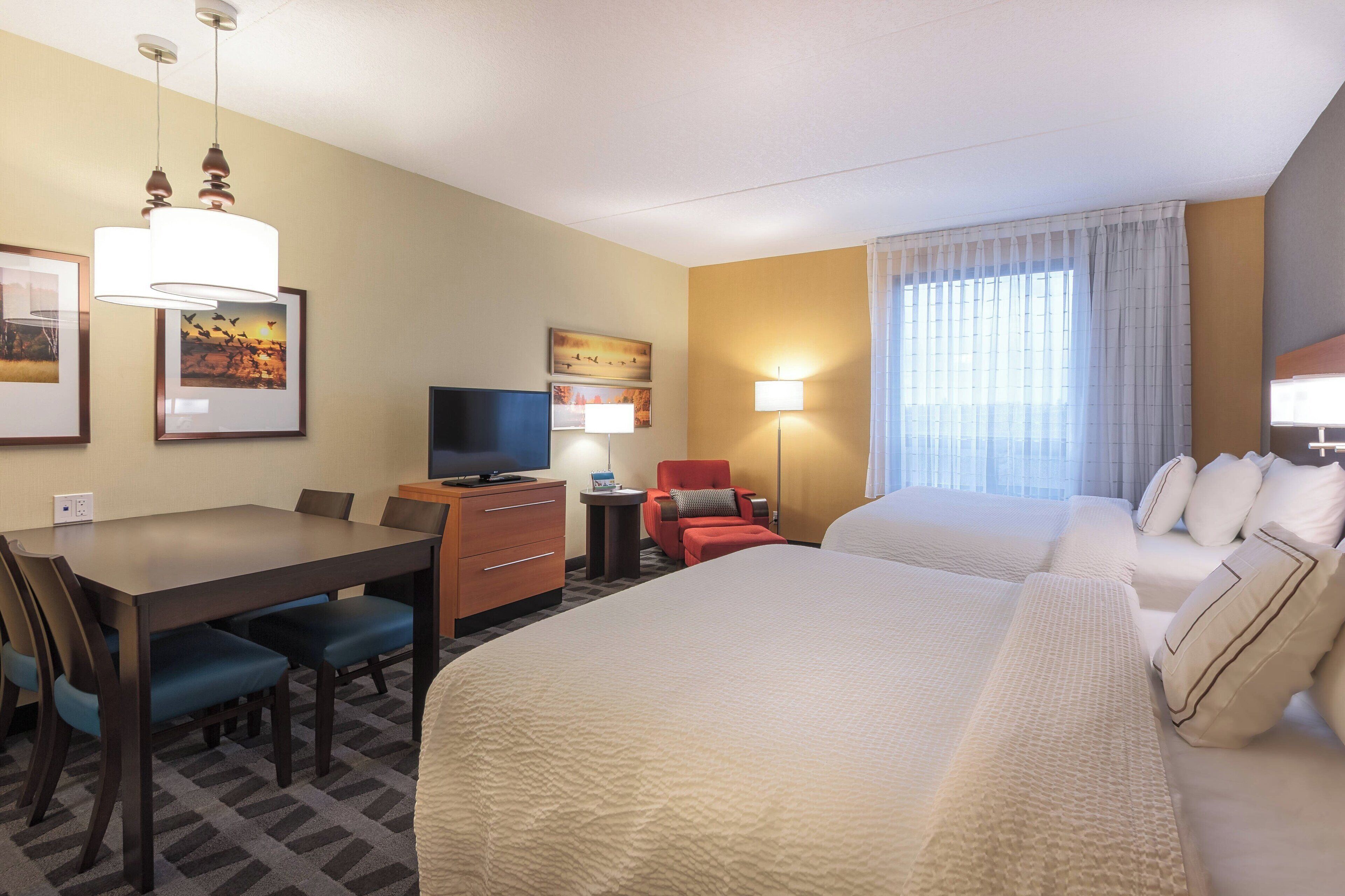 Une chambre d’hôtel avec un grand lit, un bureau avec une chaise, une télévision et une petite table avec une lampe.