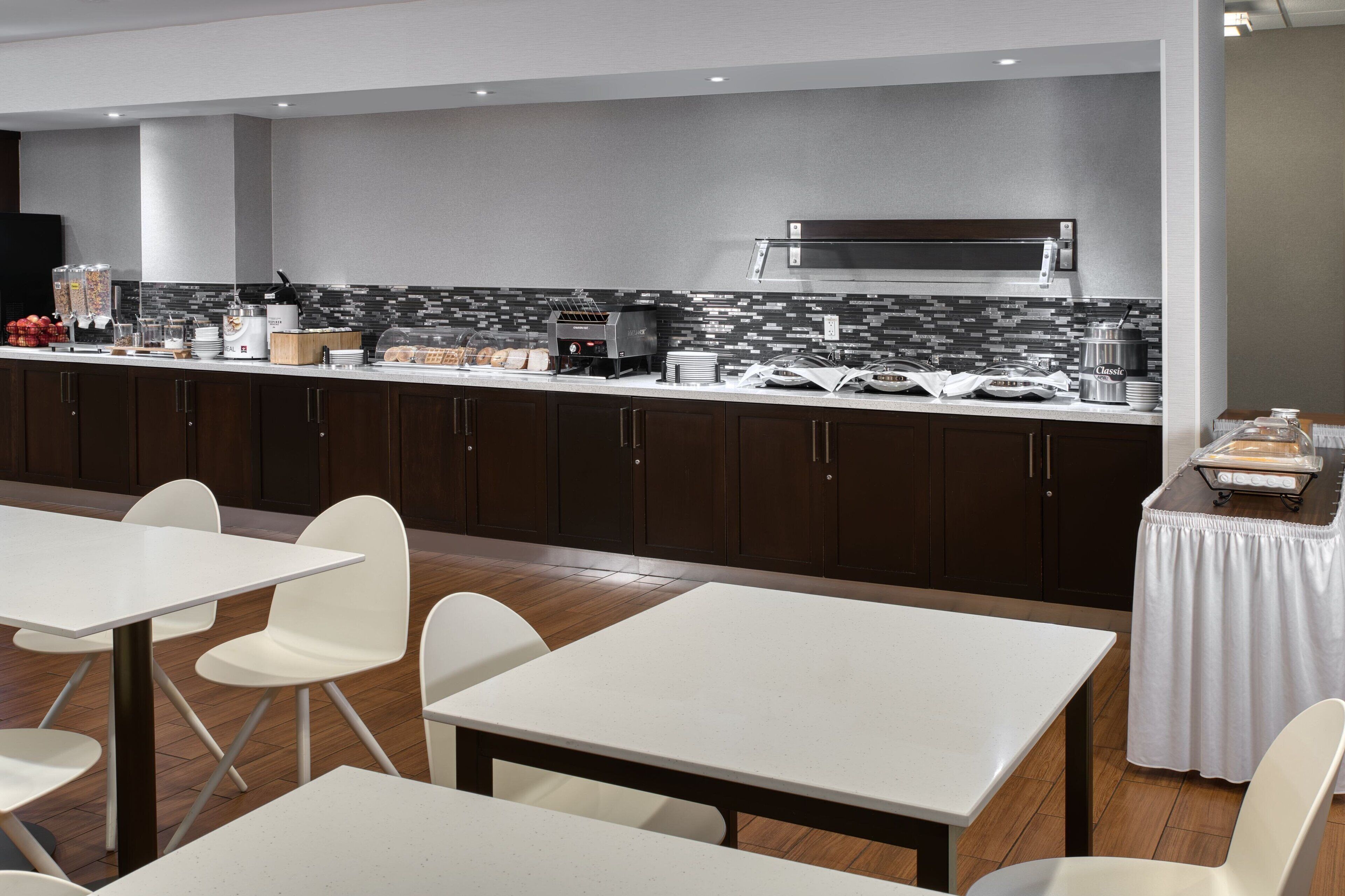 Een moderne keuken met een marmeren achterwand, roestvrijstalen apparatuur en een buffetopstelling.