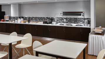 Een moderne keuken met een marmeren achterwand, roestvrijstalen apparatuur en een buffetopstelling.
