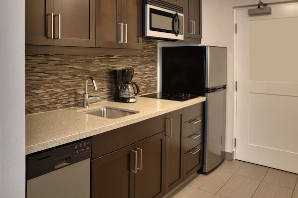 Una cocina moderna con electrodomésticos de acero inoxidable, lavavajillas y cafetera.