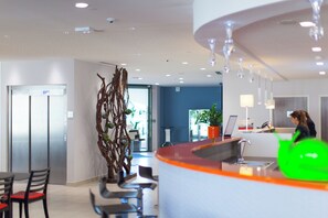 A modern hotel lobby with a reception desk, seating area, and a decorative wall. - Holiday Inn Express Toulon - Est by IHG (Toulon)