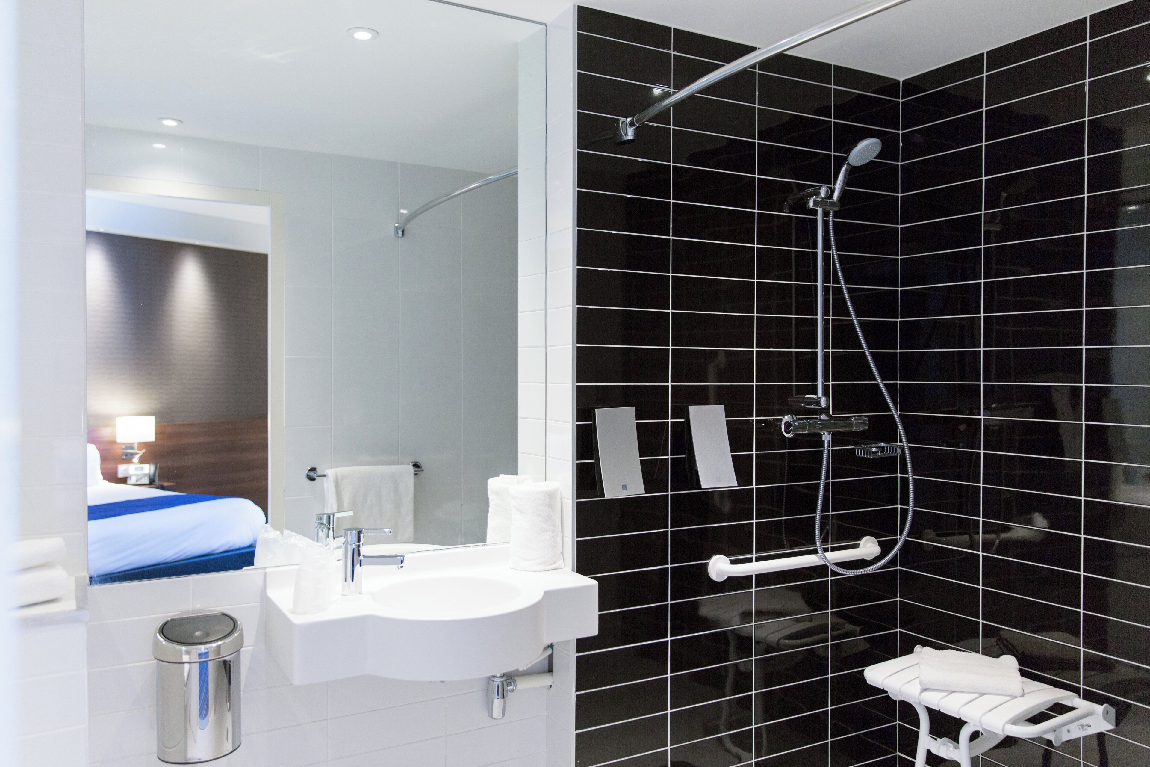 Ein modernes Badezimmer mit Waschbecken, Spiegel und Dusche inklusive Duschbrause.