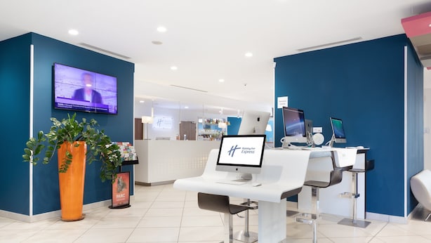 A modern dental clinic with a reception desk, computers, and a TV screen.