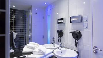 A modern bathroom with two sinks, a hairdryer, and a mirror.