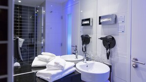 A modern bathroom with two sinks, a hairdryer, and a shower area.