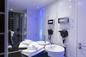 A modern bathroom with two sinks, a hairdryer, and a shower area. - Holiday Inn Express Toulon - Est by IHG (Toulon)