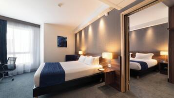A modern hotel room with a large bed, bedside tables, a desk, and a chair.