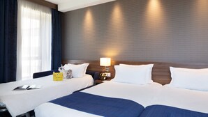 A hotel room with two beds, a bedside table with a lamp, a telephone, and a decorative item on the left side. - Holiday Inn Express Toulon - Est by IHG (Toulon)